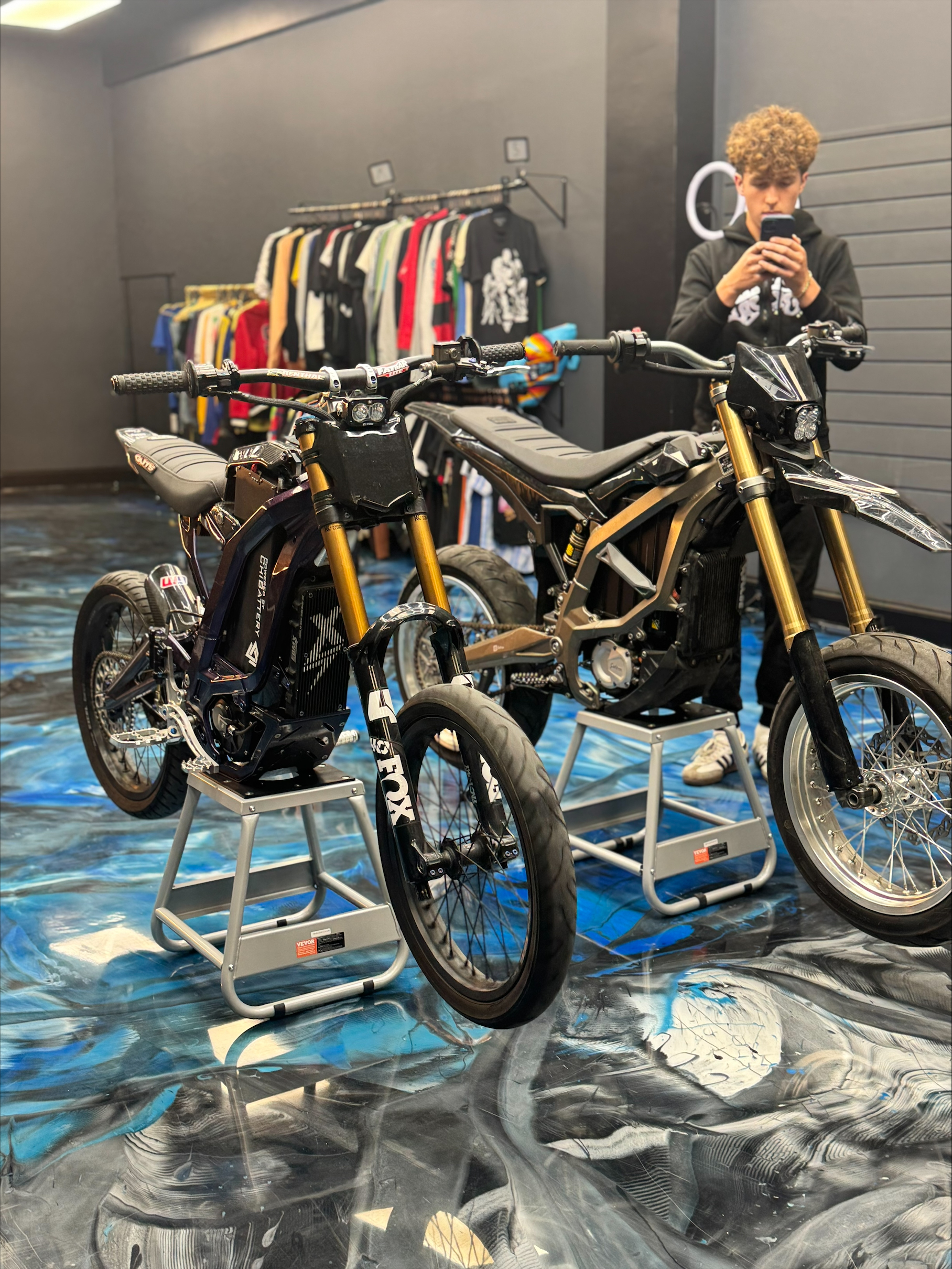 Two electric bikes staged inside the SoFlo E-Moto shop with vintage shirts behind them