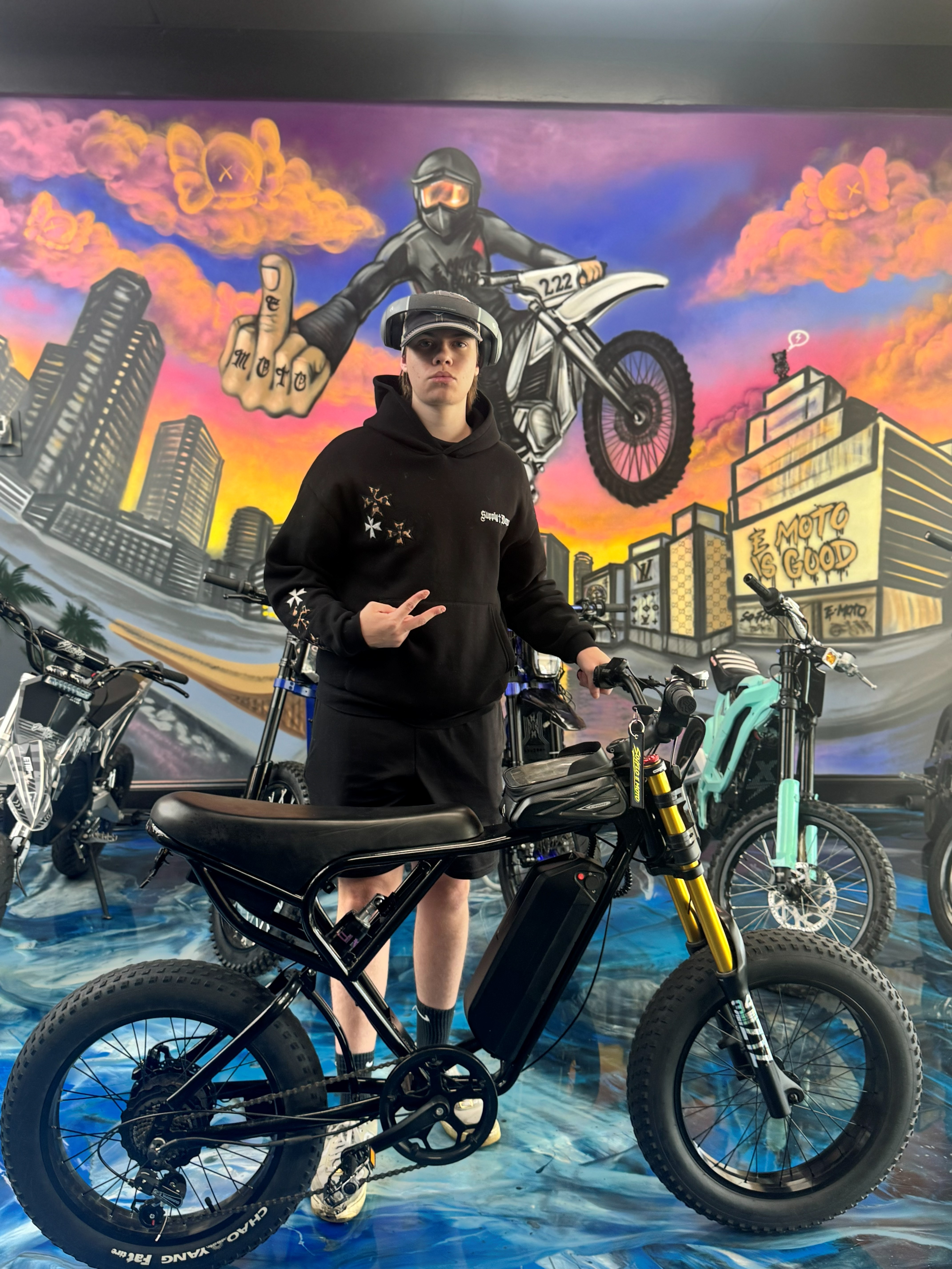 SoFlo E-Moto rider posing in front of the mural wall inside the shop