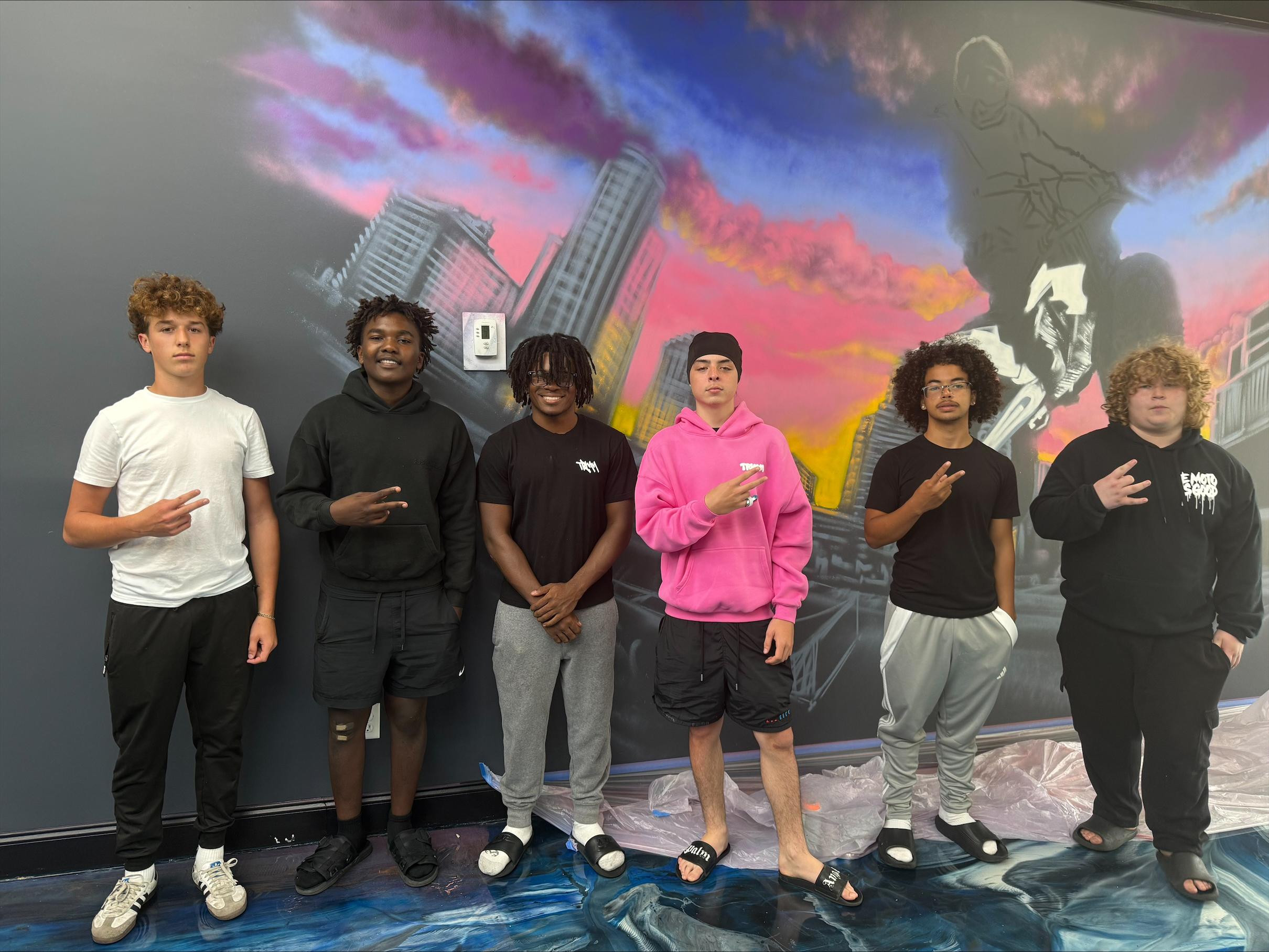 SoFlo E-Moto crew standing in front of a colorful mural wall inside the shop