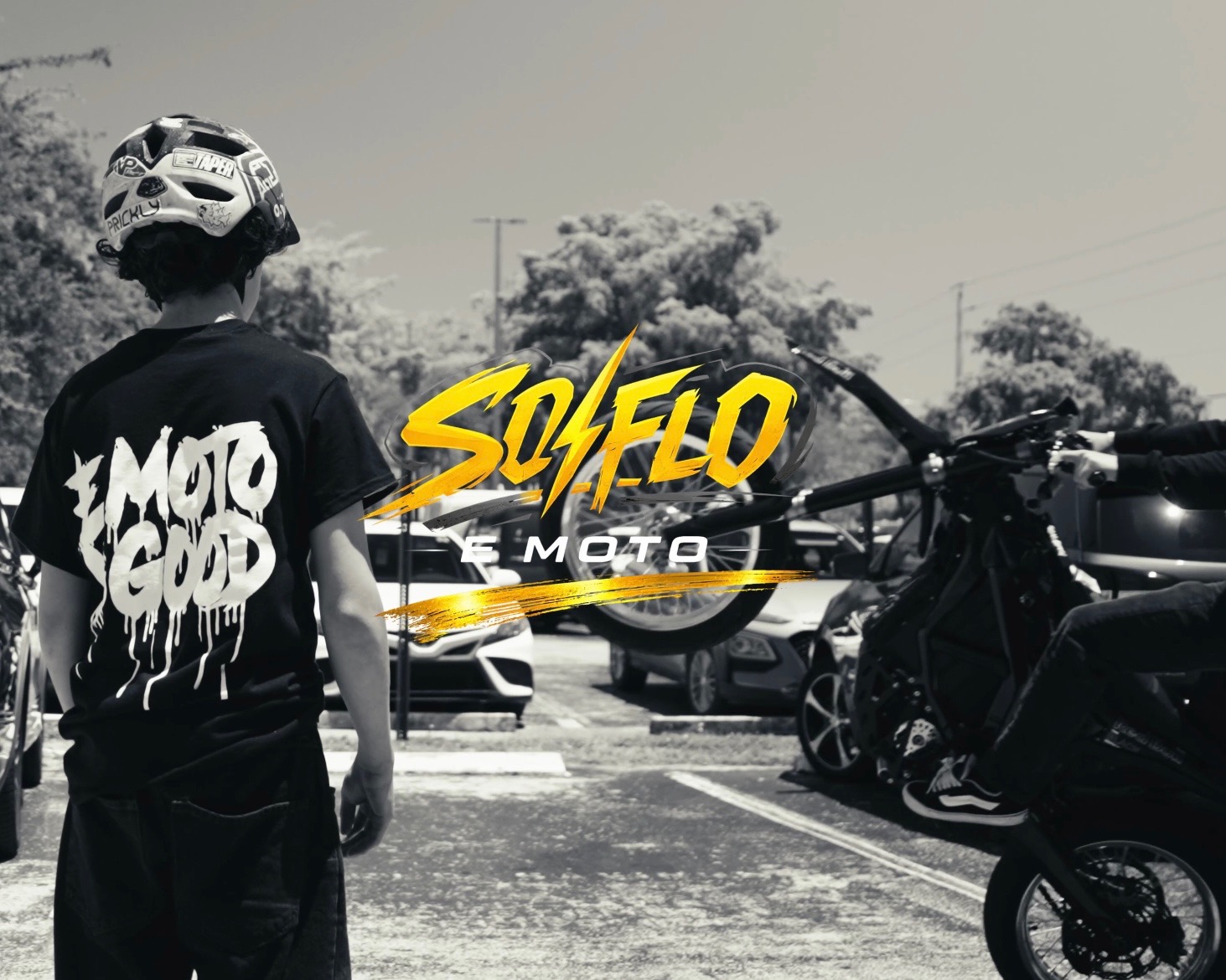 Black and white SoFlo E-Moto rider scene with a gold SoFlo E-Moto logo over the center.
